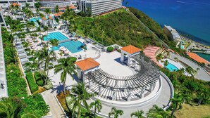 A resort with multiple swimming pools, palm trees, and a large circular building.