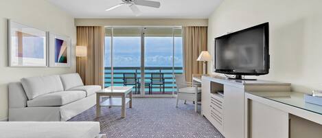 A hotel room with a balcony, a bed, a TV, a desk, and a sofa.