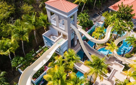A resort with a water slide, a pool, and lush greenery.