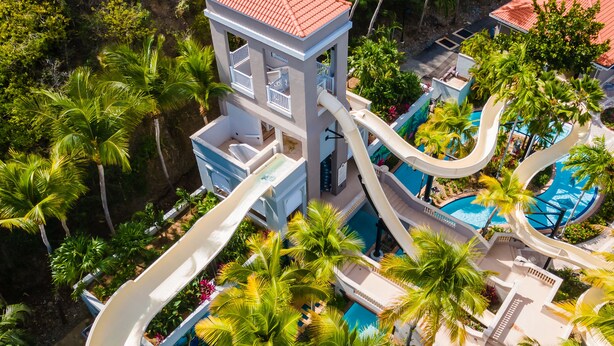 A resort with a water slide, a pool, and lush greenery.