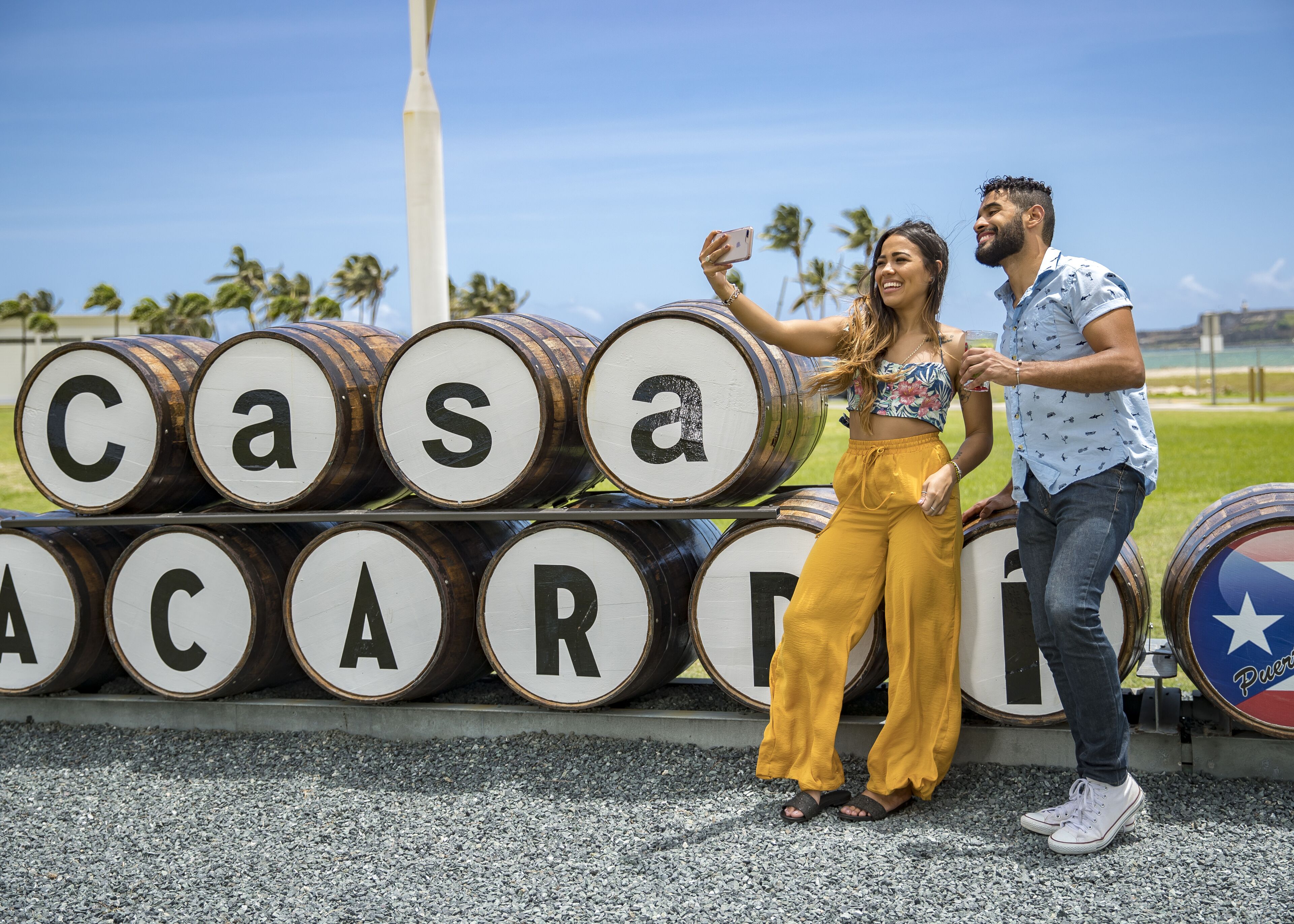 A couple taking a selfie in front of barrels with letters spelling out "Casa Acadia."