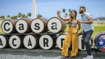 Una pareja tomándose un selfie frente a barriles con letras que forman el nombre 'Casa Acadia'.