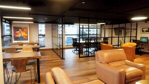 A modern office space with wooden tables, leather chairs, and glass partitions. - Bogota Plaza Hotel  (Bogotá)
