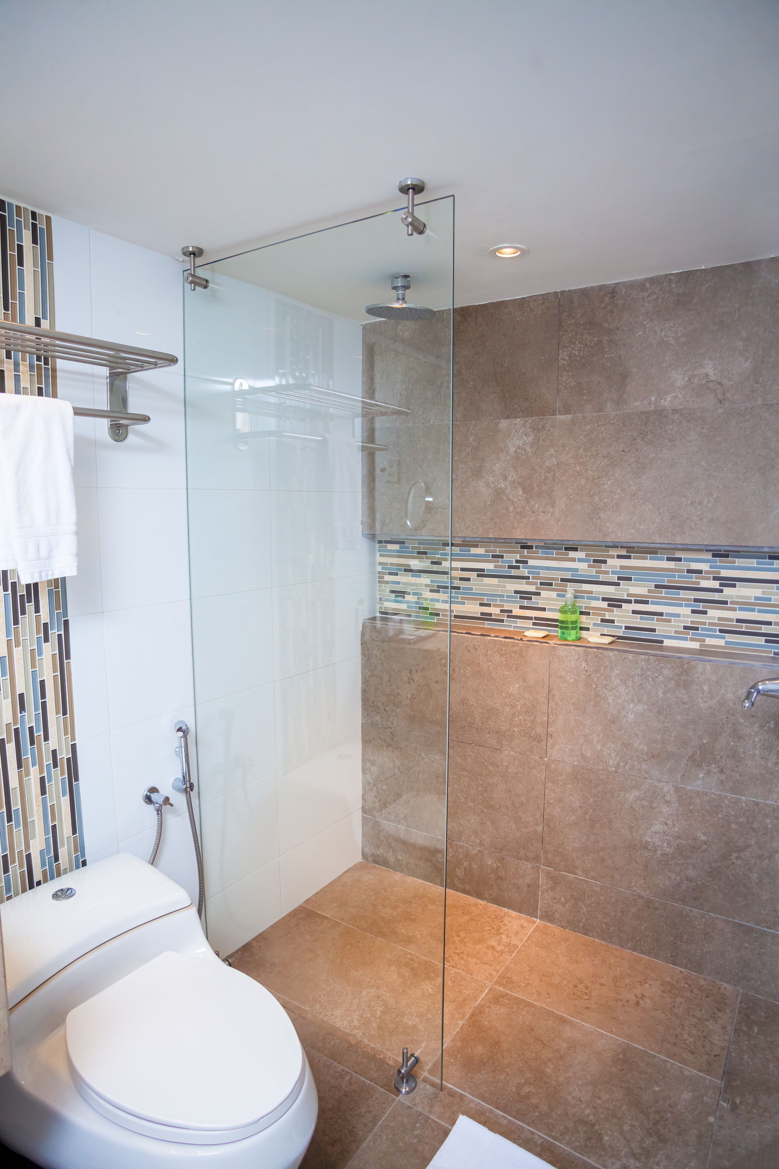 A modern bathroom with a glass-enclosed shower, a white toilet, and a tiled backsplash.