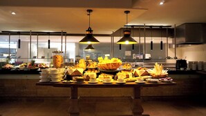 Montaje de bufé con diferentes alimentos y una cocina moderna al fondo.