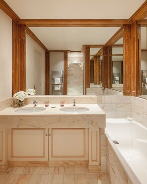 Une salle de bain dotée d’un grand lavabo en marbre, d’une baignoire et de poutres en bois au plafond.