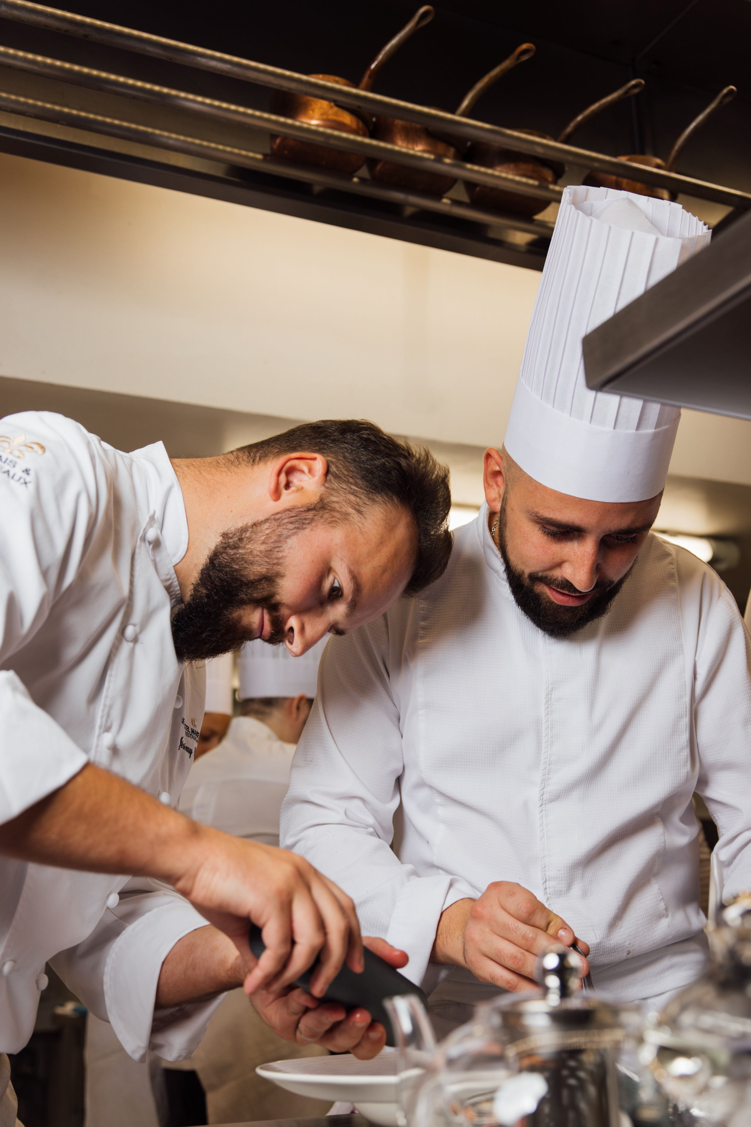 Dos chefs en un ambiente de cocina profesional, concentrados en la preparación de alimentos.