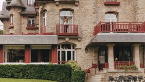 Un bâtiment en pierre doté de nombreux balcons, de grandes fenêtres et d’une tourelle.