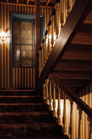 Una escalera con balaustres de madera y un papel tapiz decorado.