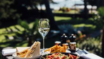 A table set with a sandwich, fries, a salad, a wine glass, and condiments.