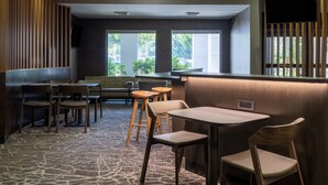 A restaurant with a stone-patterned floor, wooden furniture, and large windows offering a view of the outdoors. - SpringHill Suites by Marriott Pasadena Arcadia (Arcadia)
