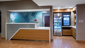 A modern reception area with a wooden counter, a blue textured wall, and a vending machine. - SpringHill Suites by Marriott Pasadena Arcadia (Arcadia)