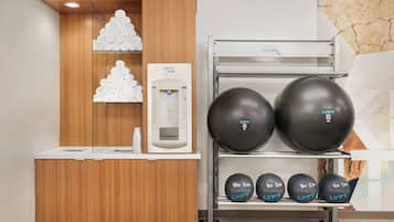 A reception area with a wooden counter, a hydration station, and a rack of exercise balls.