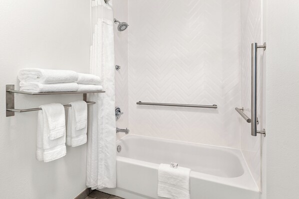 A modern bathroom with a bathtub, a shower, and a towel rack with folded towels. - Holiday Inn & Suites Bothell by IHG (Bothell)