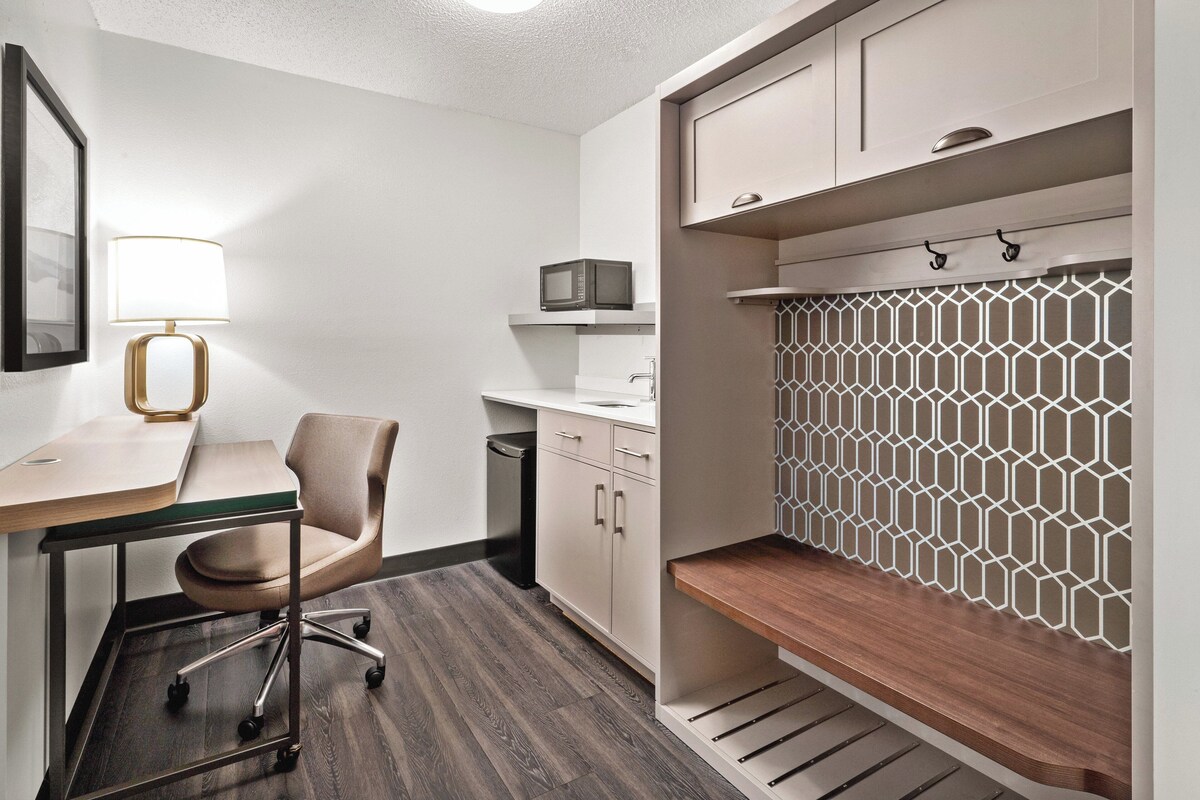 Een moderne kitchenette met een magnetron, een spoelbak en een kast met een geometrisch patroon als achterwand.