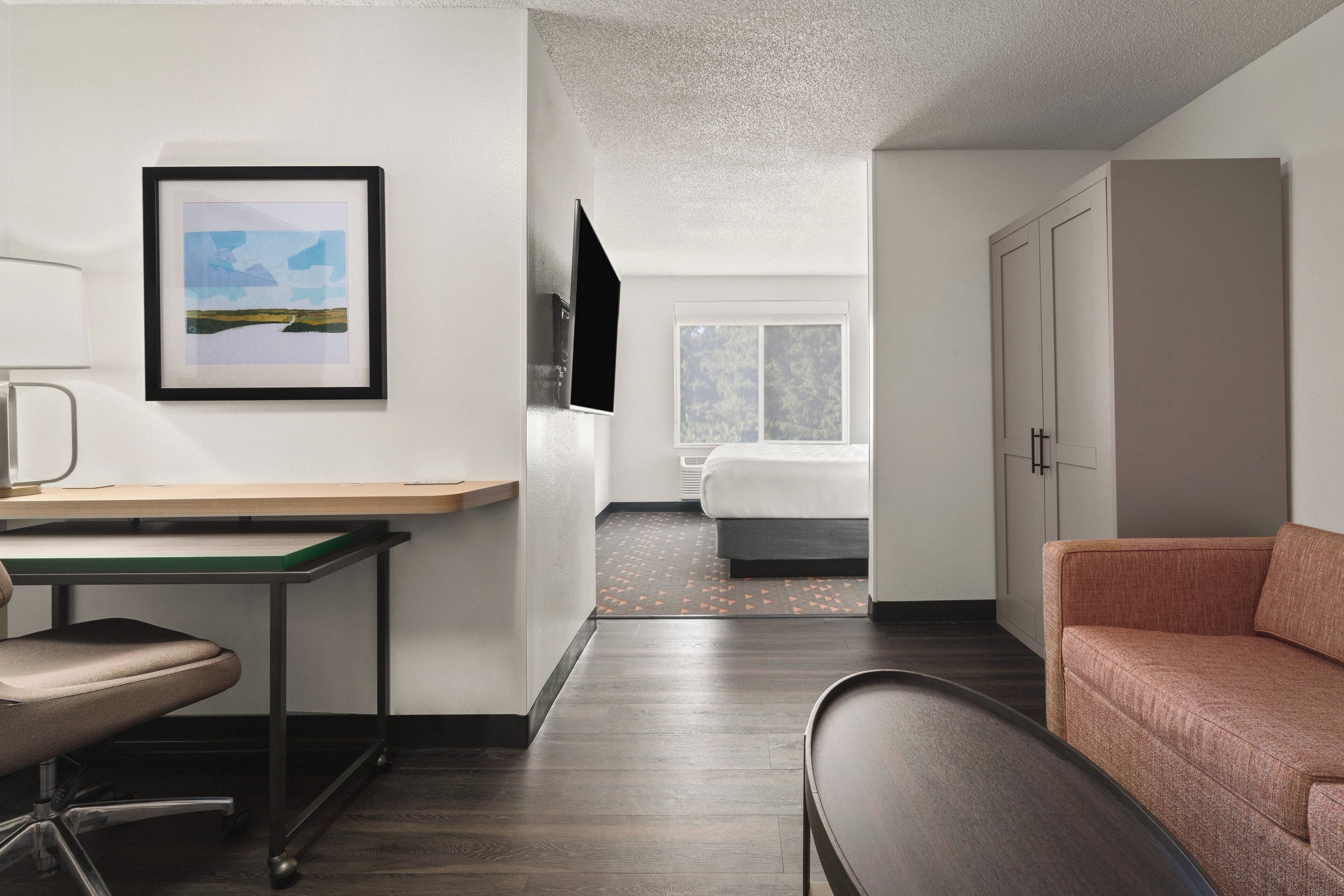 Una habitación de hotel moderna con escritorio, silla, cama y sofá.