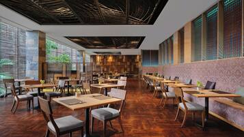 A spacious restaurant with wooden tables and chairs, a high ceiling with exposed beams, and large windows allowing natural light.