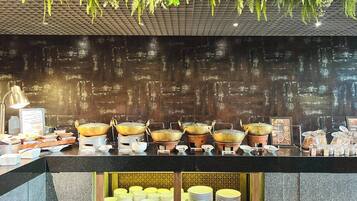 A buffet setup with multiple serving stations, including pots and bowls, and a variety of food items.