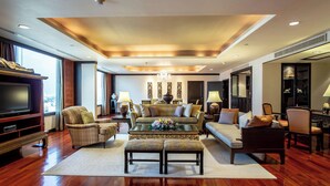 A spacious living room with a large flat-screen TV, comfortable seating, and a decorative chandelier. - Jubilee Prestige Hotel Ratchadapisek (Bangkok)