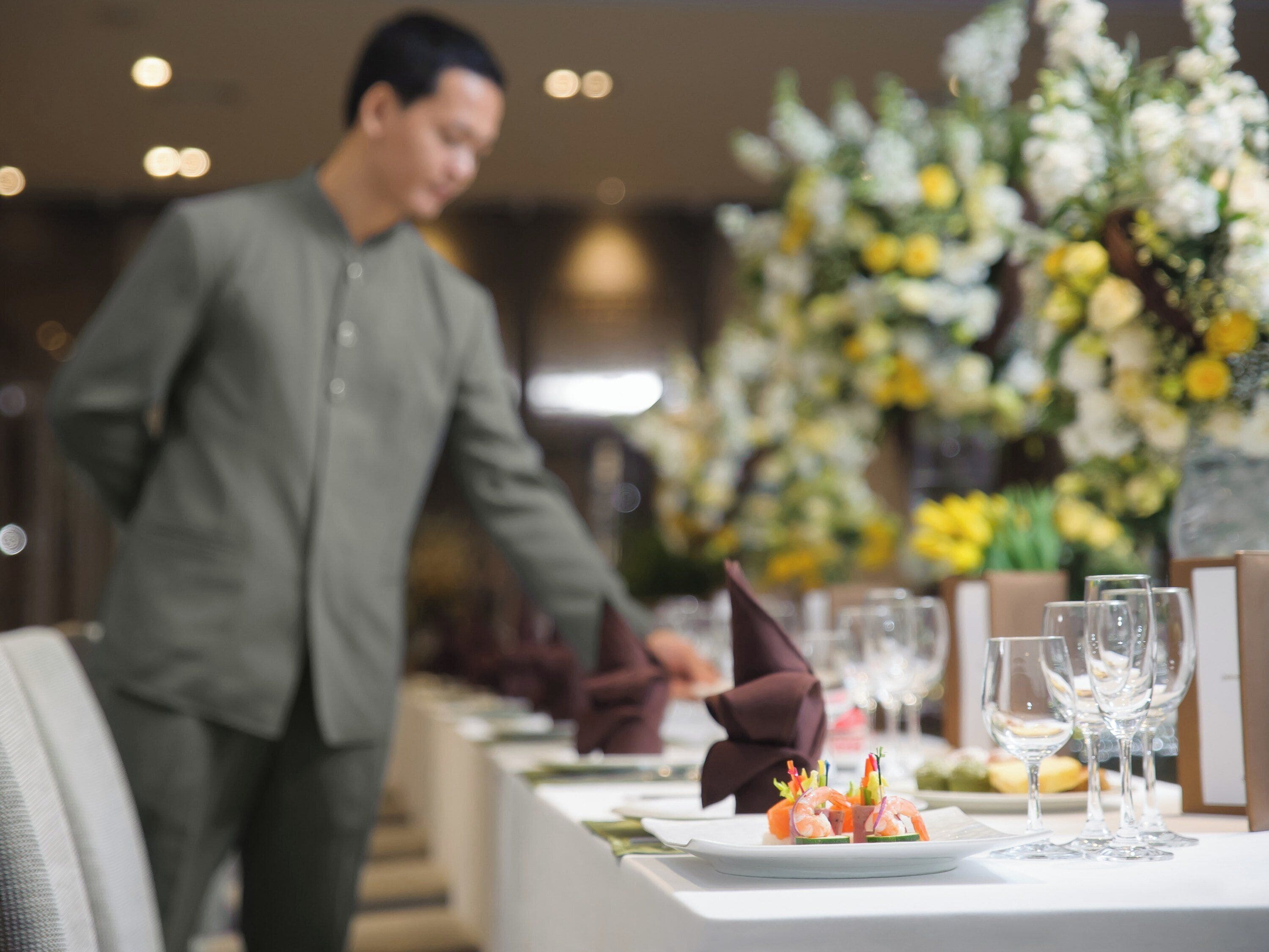 A restaurant setting with a waiter serving a dish.