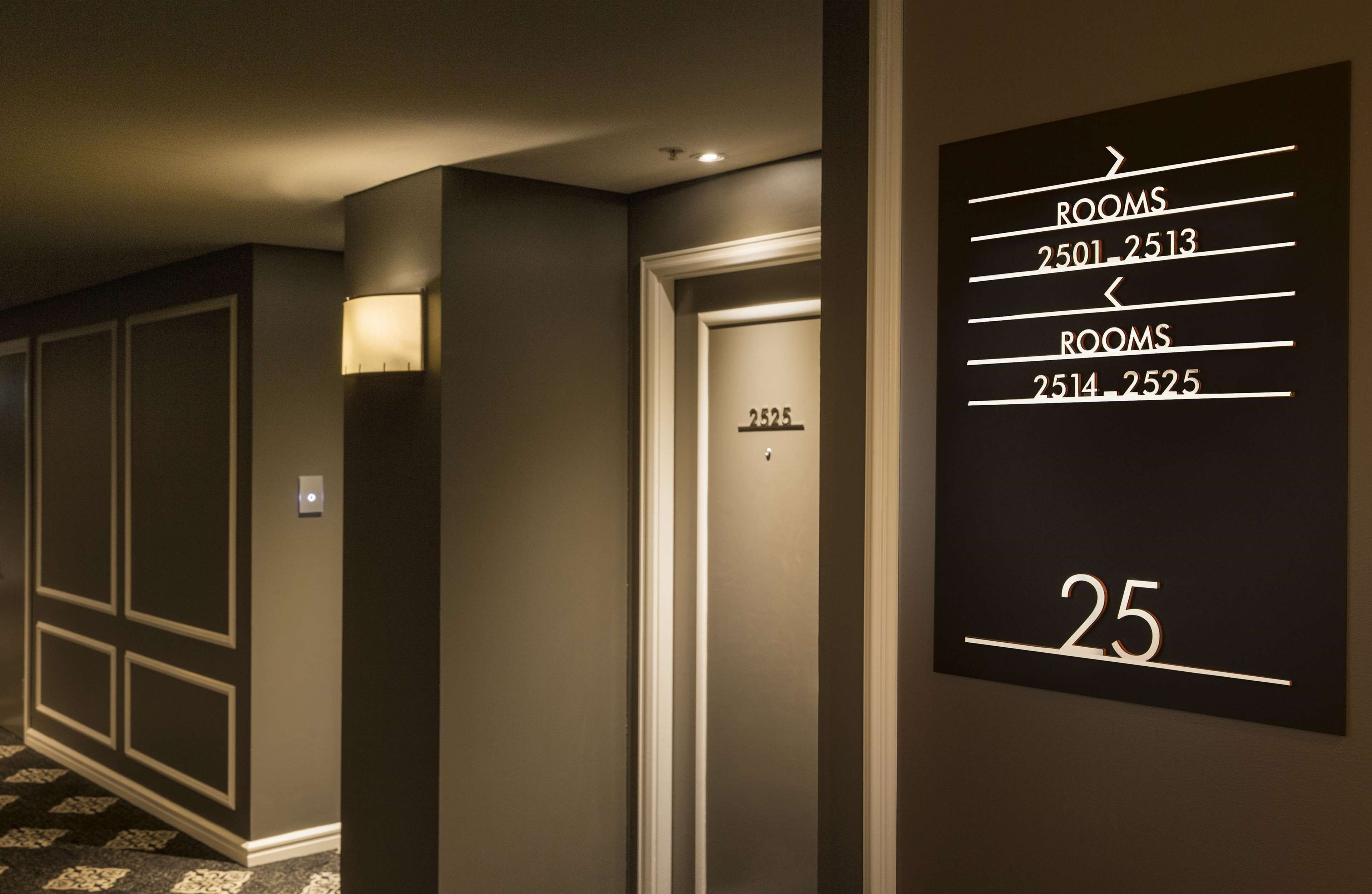 A hotel hallway with a sign indicating room numbers 25, 2514-2525, and 2501-2513.