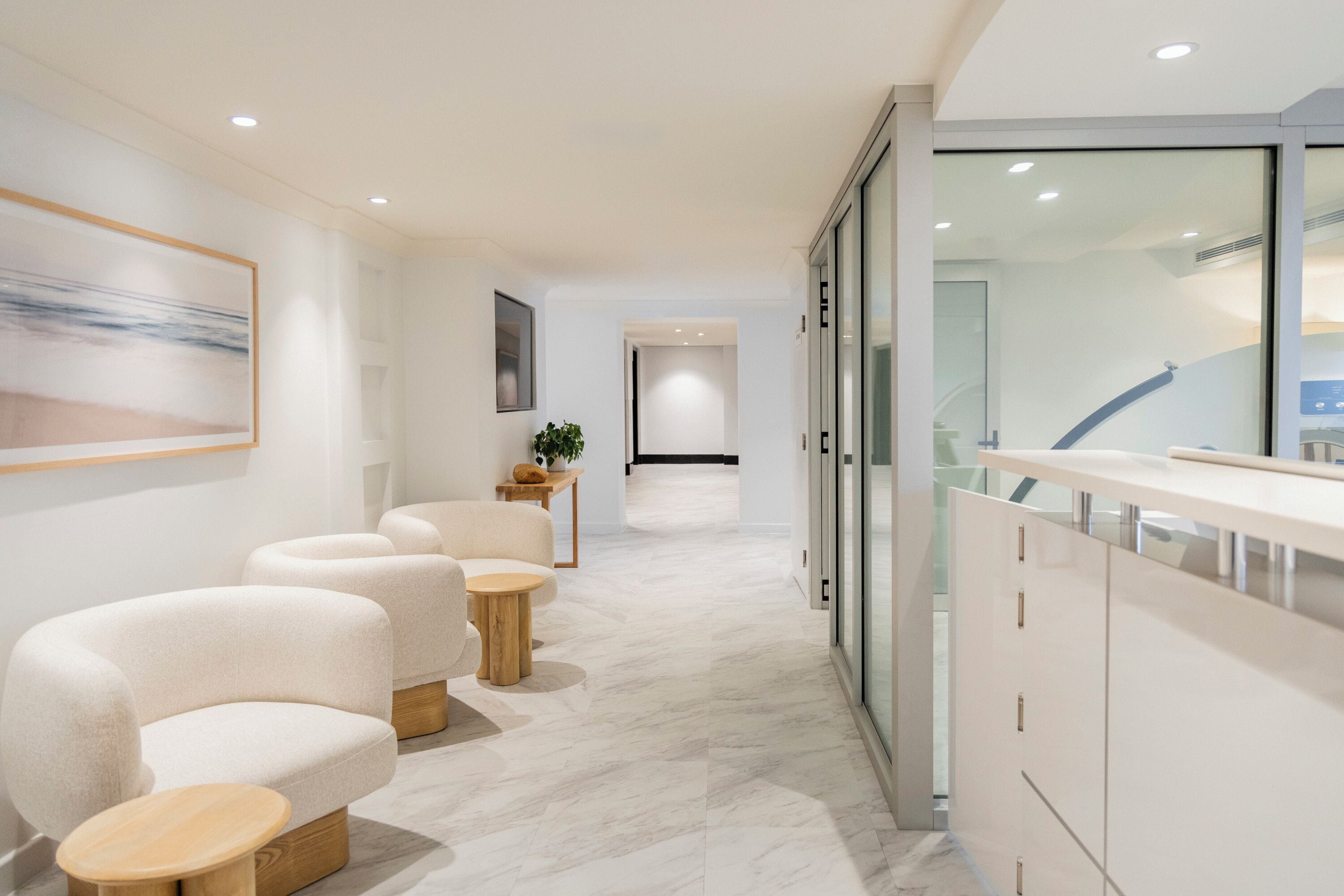 A modern hotel corridor with a seating area, a reception desk, and a view of the interior.