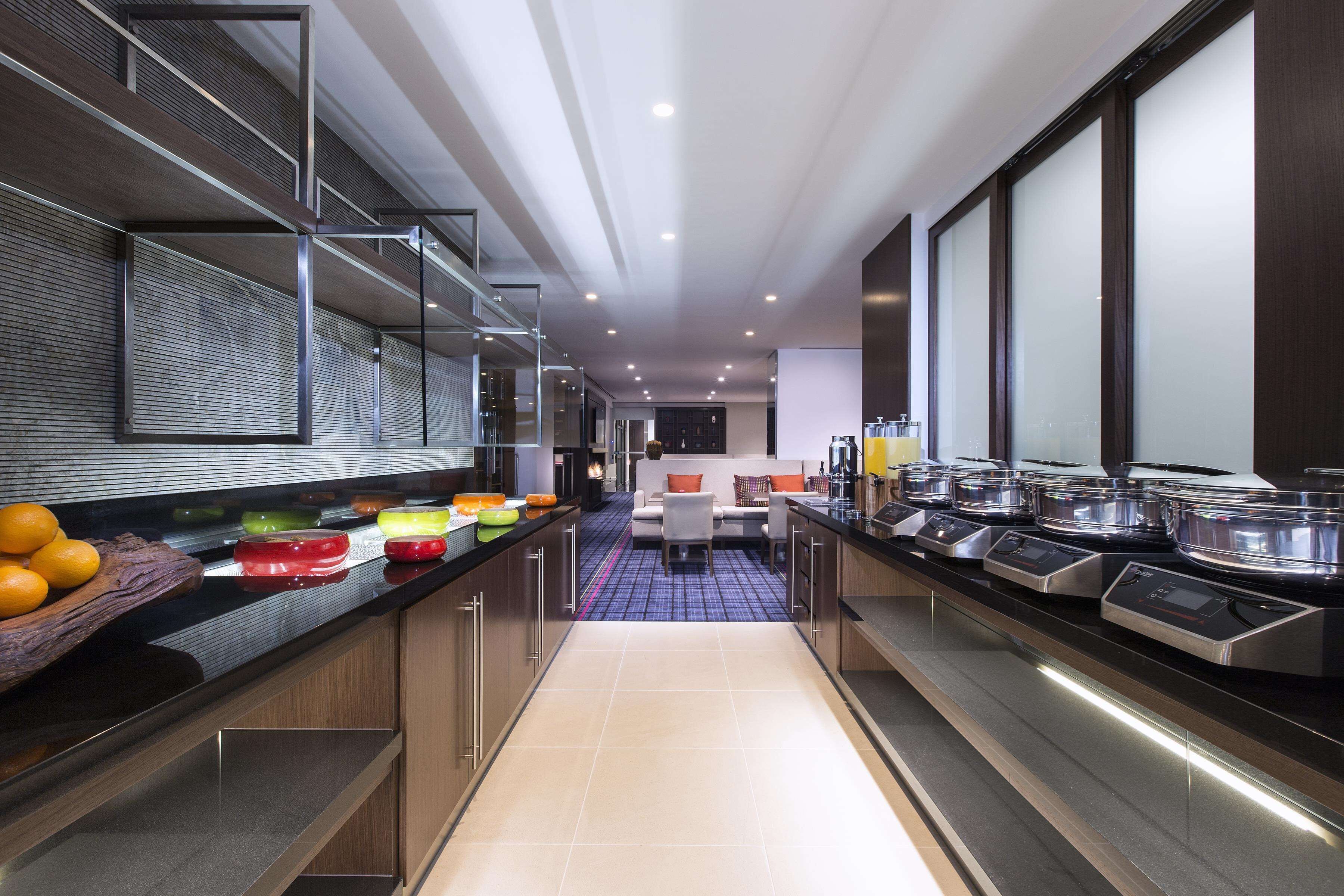 A modern kitchen with a long counter, a central island, and a seating area with a sofa and chairs.