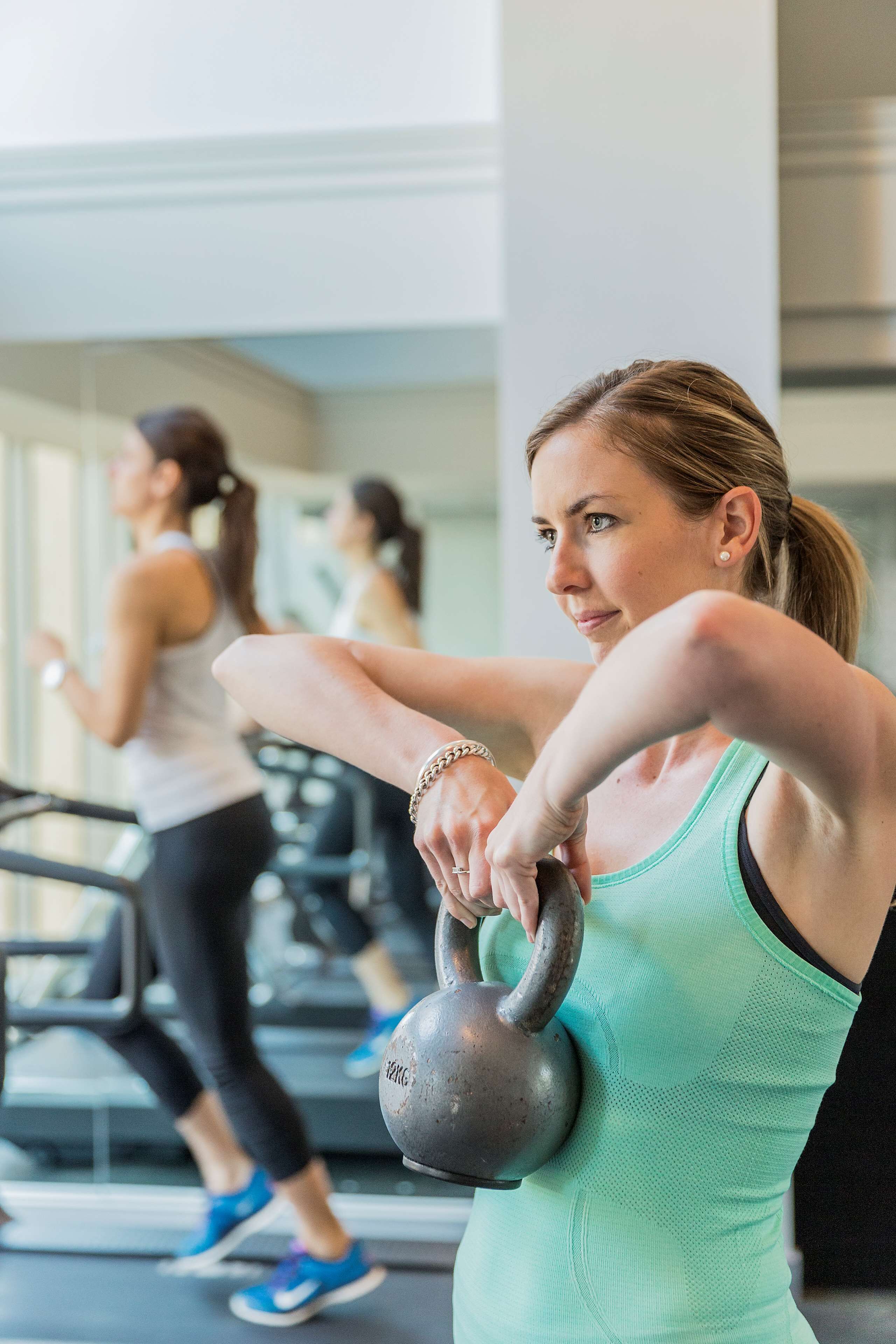 A gym with treadmills and a person lifting a kettlebell.