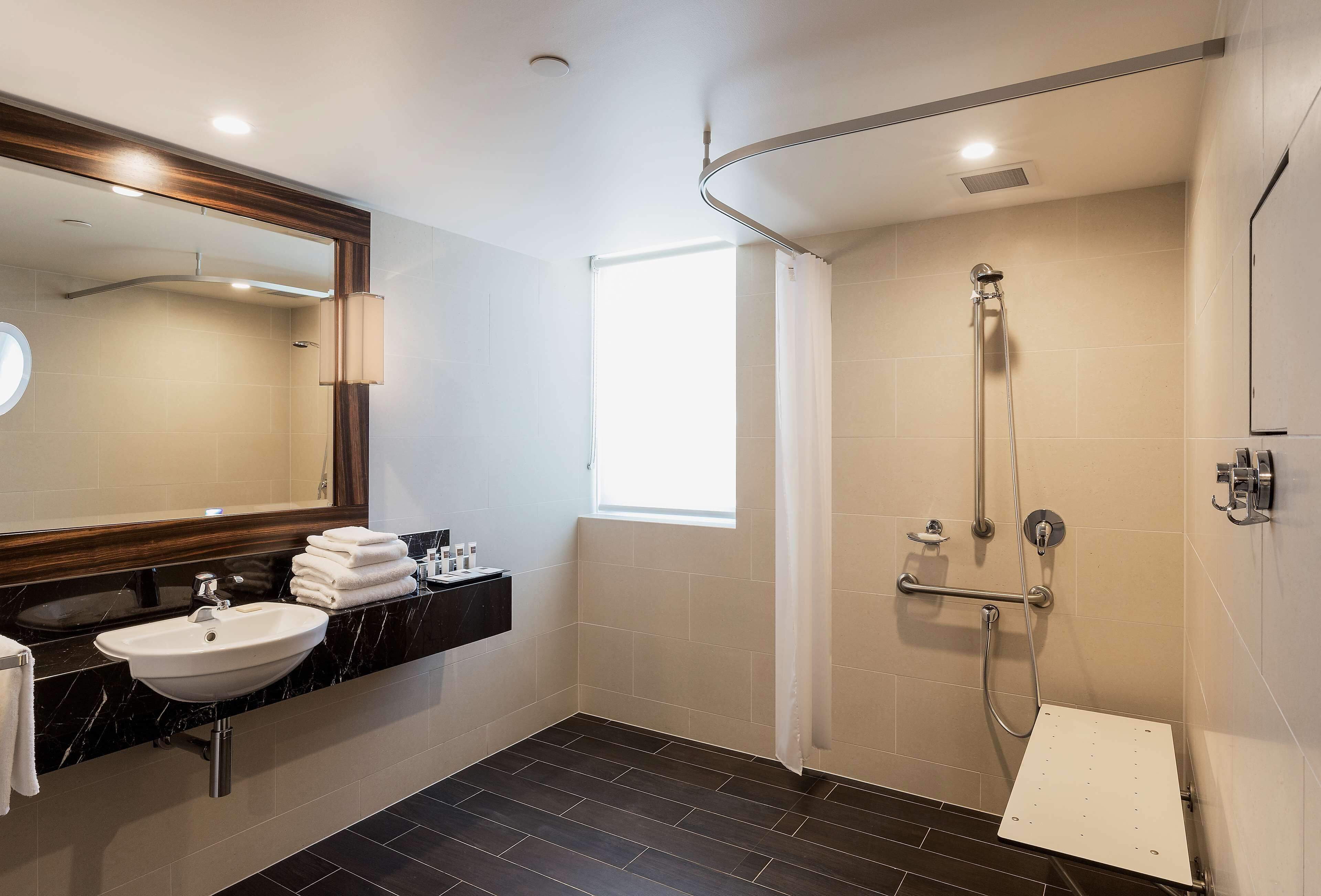 A modern bathroom with a sink, mirror, and shower.