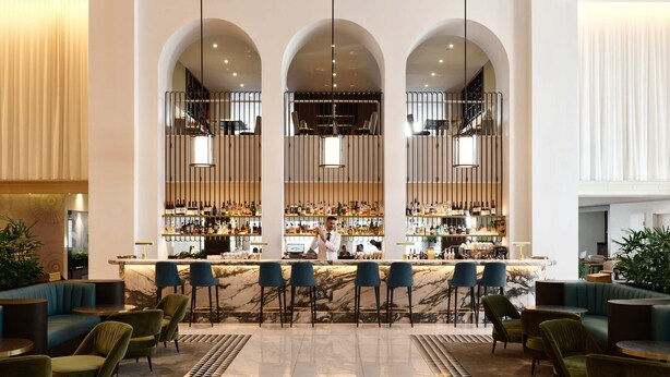 A bar area with a marble countertop, multiple bar stools, and a bartender. - Swissotel Sydney (Sydney)