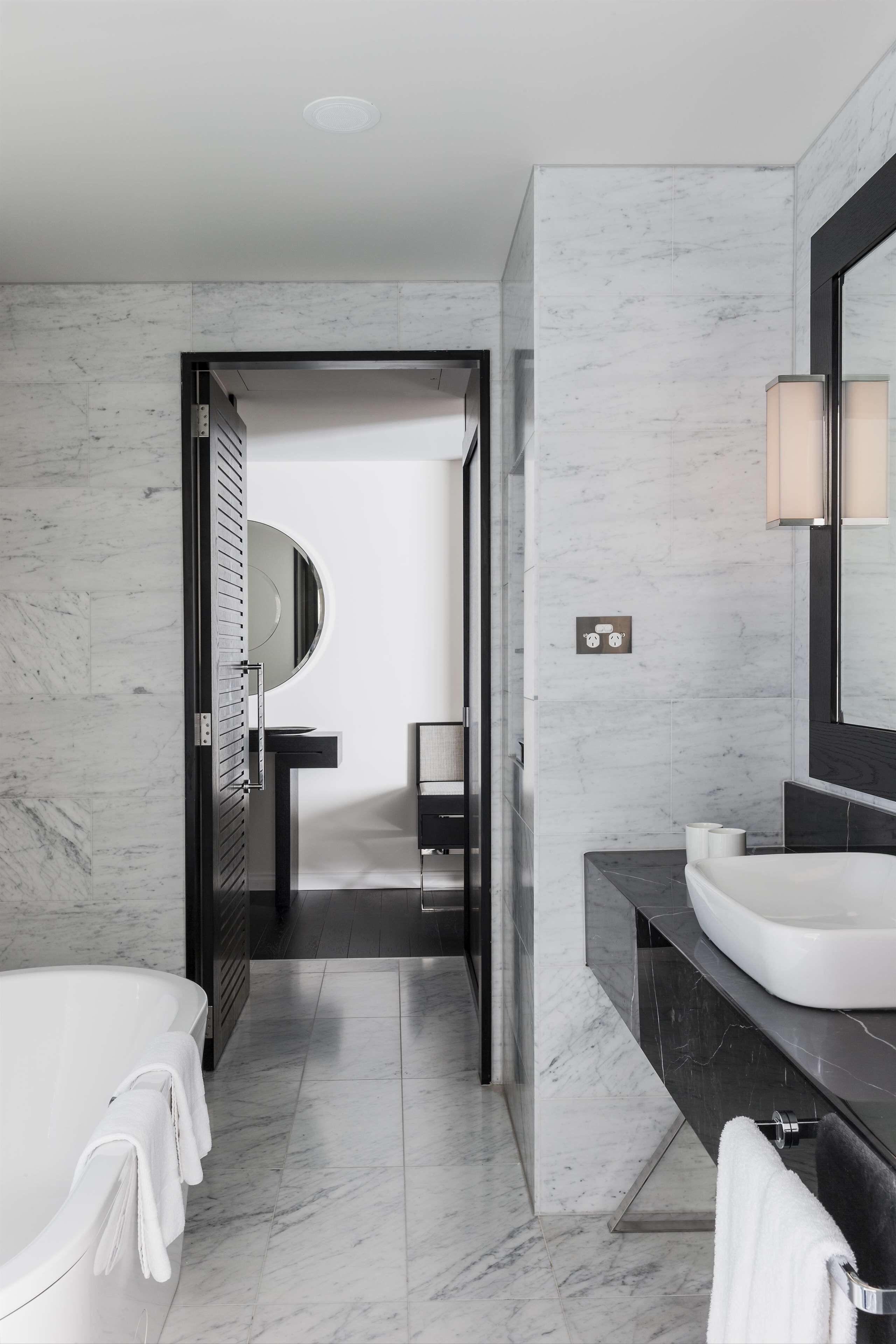 Un baño moderno con una bañera blanca, un espejo grande y un mueble de tocador negro.