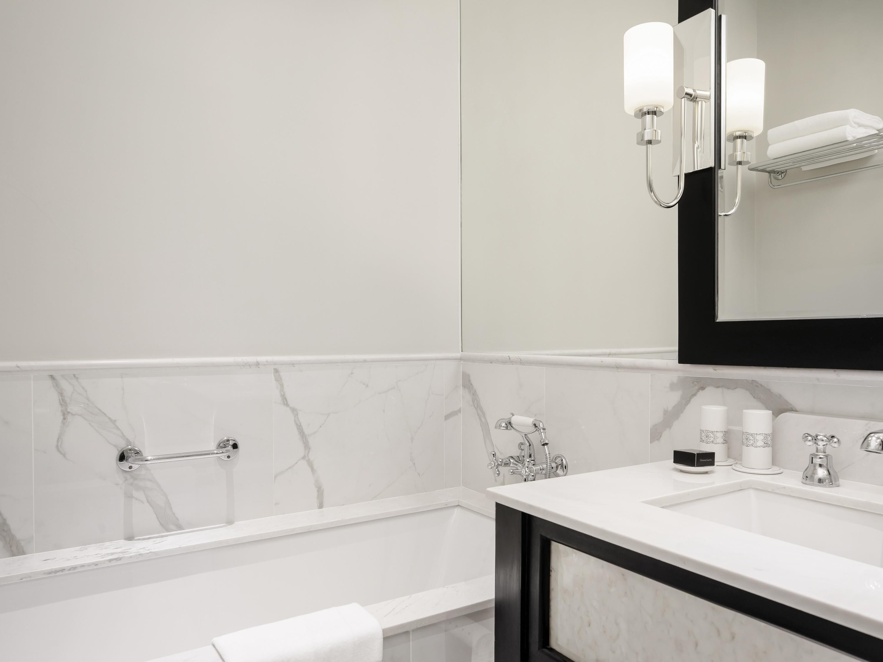 Une salle de bain moderne avec une baignoire, un meuble-lavabo avec un miroir et un porte-serviettes.