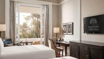 Una habitación de hotel con cama, escritorio, silla, lámpara, teléfono y televisor en la pared.