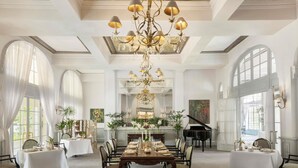 Ein prachtvoller Speisesaal mit einer Chandelüster, großen Fenstern und einem Flügel.