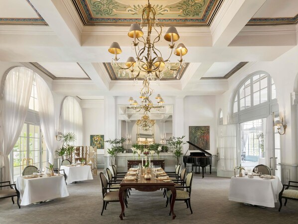 A grand dining room with a chandelier, large windows, and a grand piano.