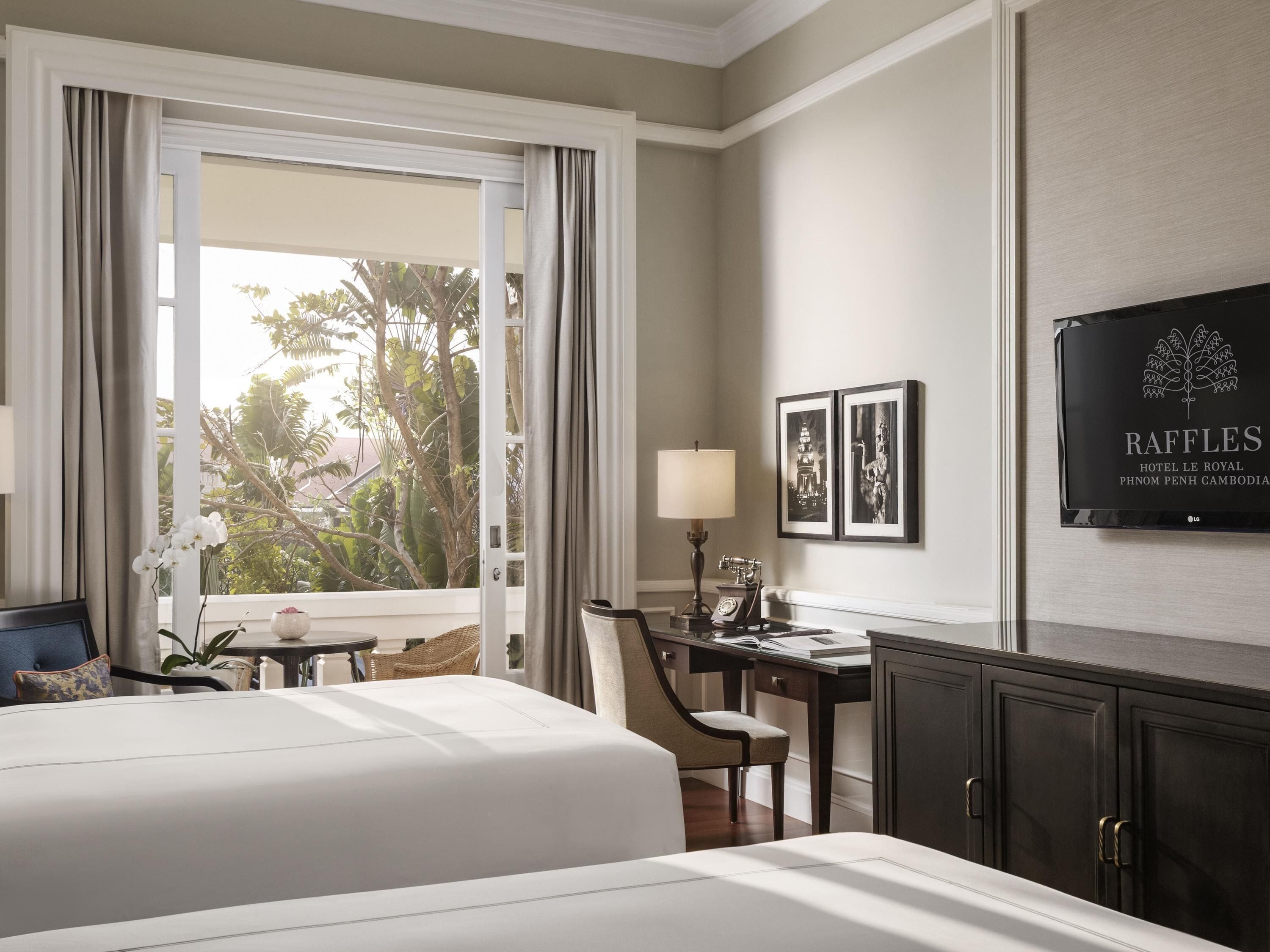 A hotel room with a bed, desk, chair, lamp, and a television on the wall.