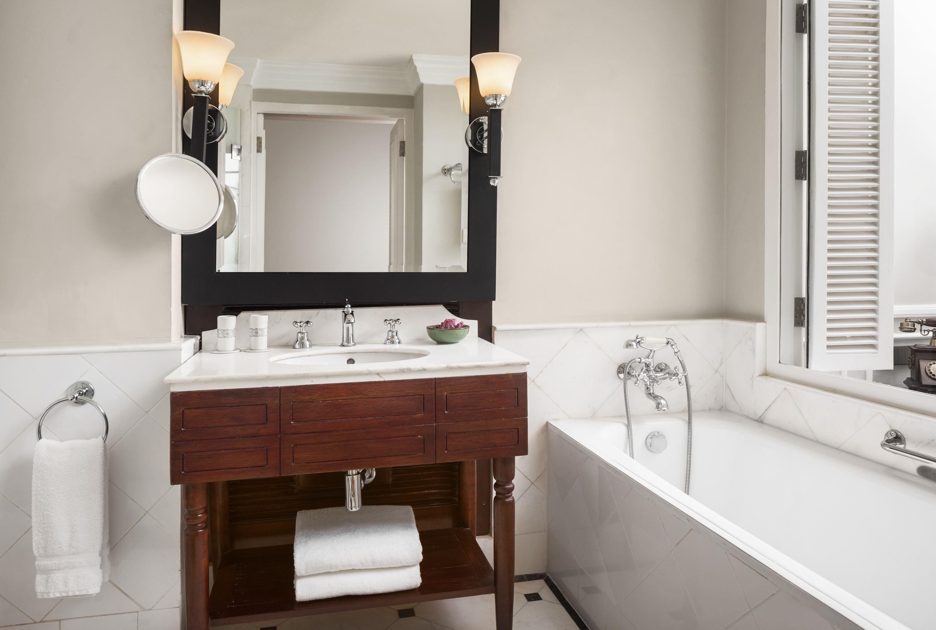 A bathroom with a white sink, dark wooden vanity, and a white bathtub.