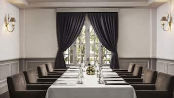 A conference room with a long table, dark curtains, and wall-mounted lamps.