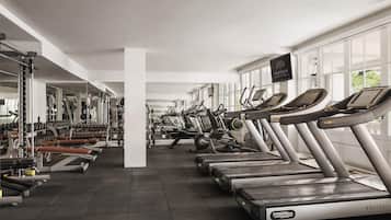 Een fitnessruimte met loopbanden, krachttrainingsapparatuur en spiegels.