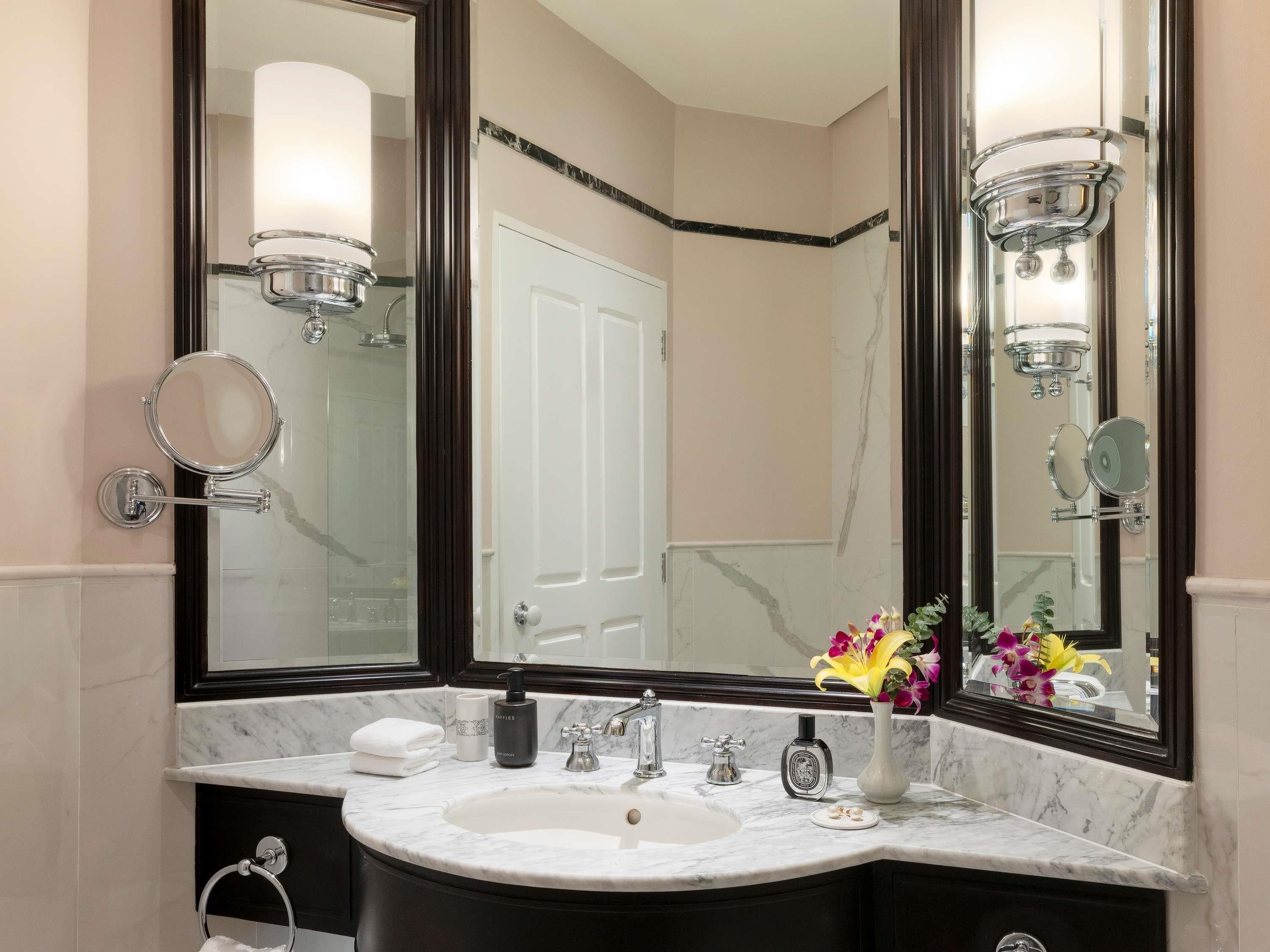 A bathroom with a large mirror, a sink, and a toilet. There are towels and toiletries on the counter.