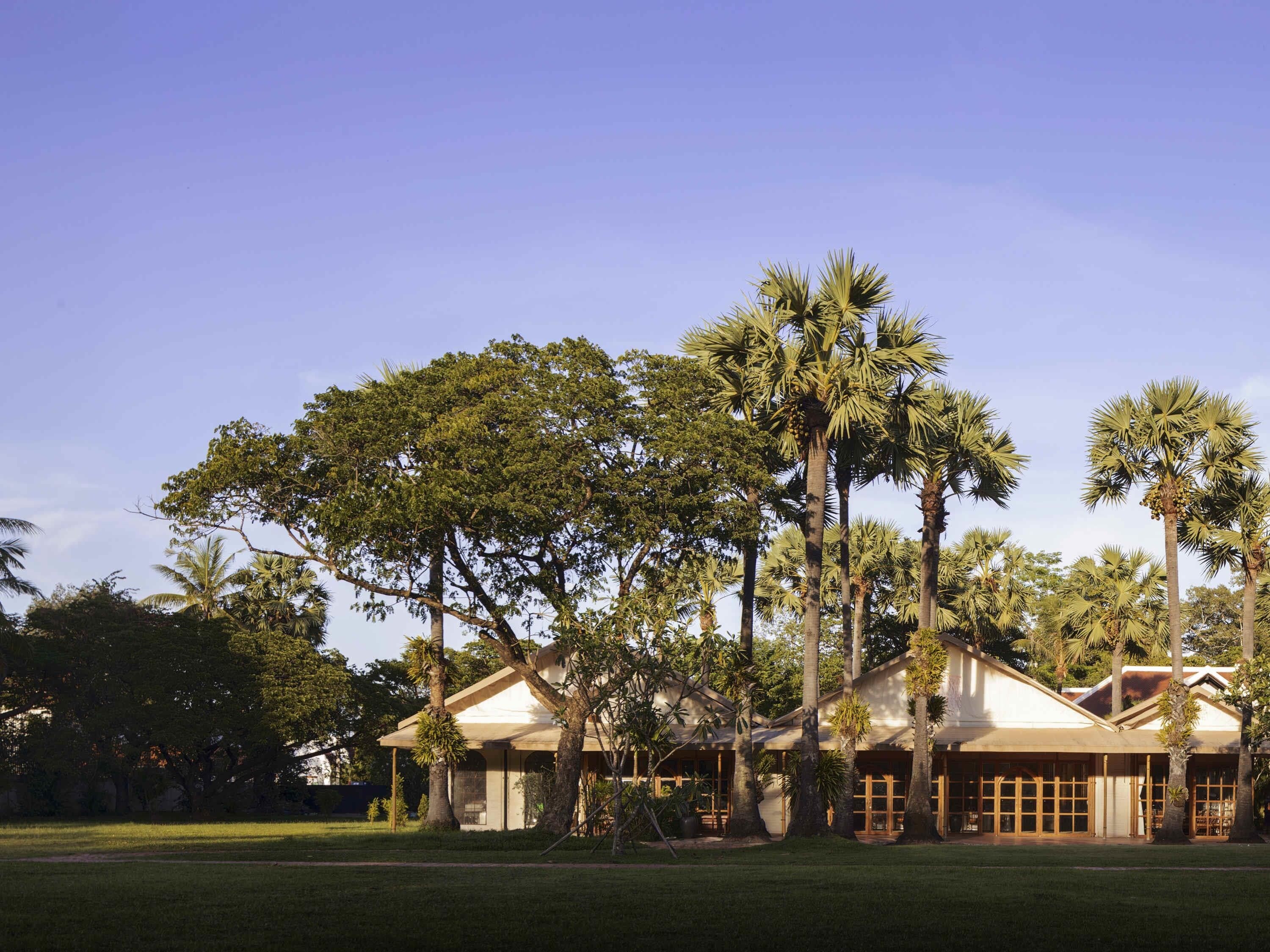 A large building with multiple rooms, surrounded by tall palm trees.