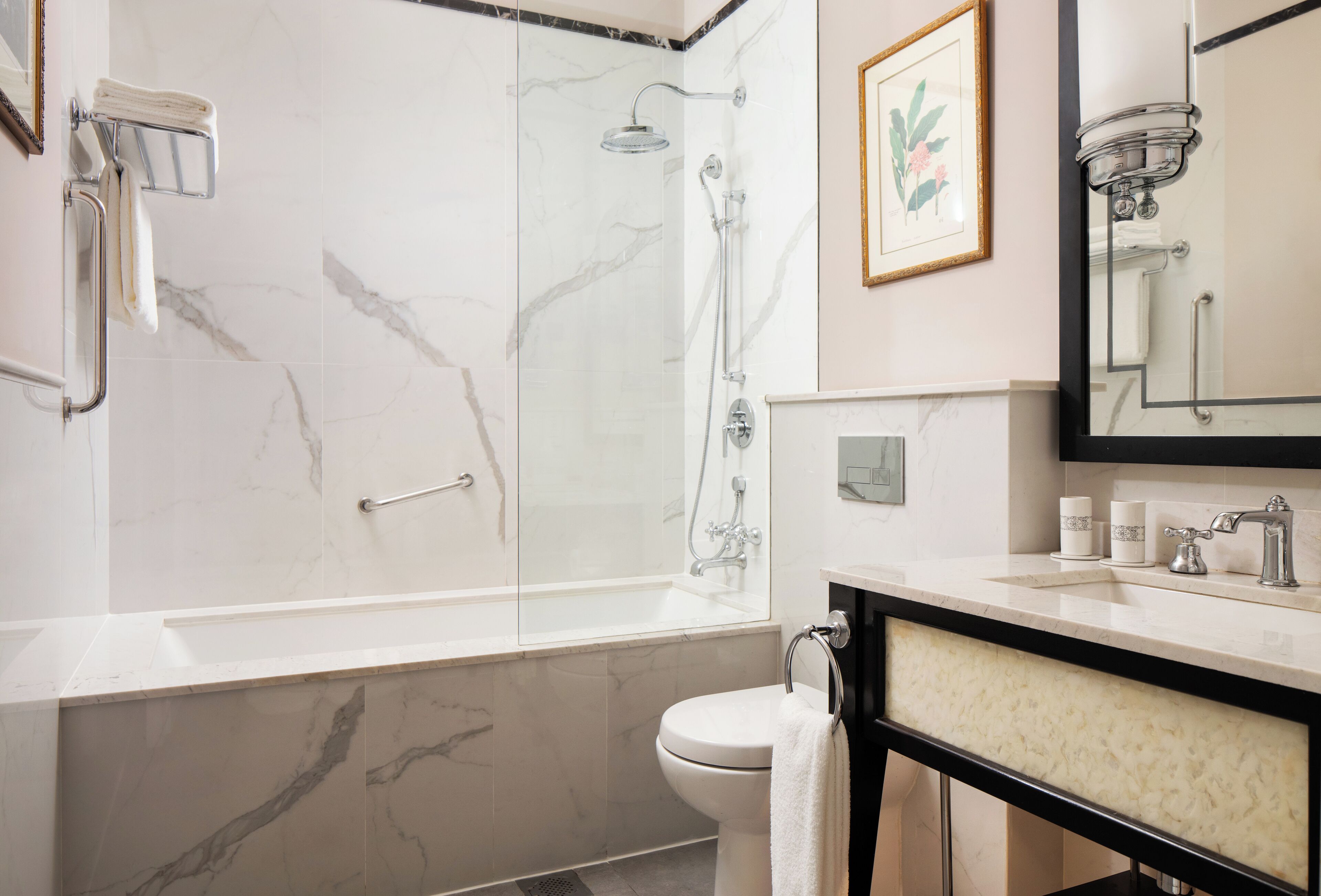 A modern bathroom with a marble shower, a toilet, a sink, and a mirror.