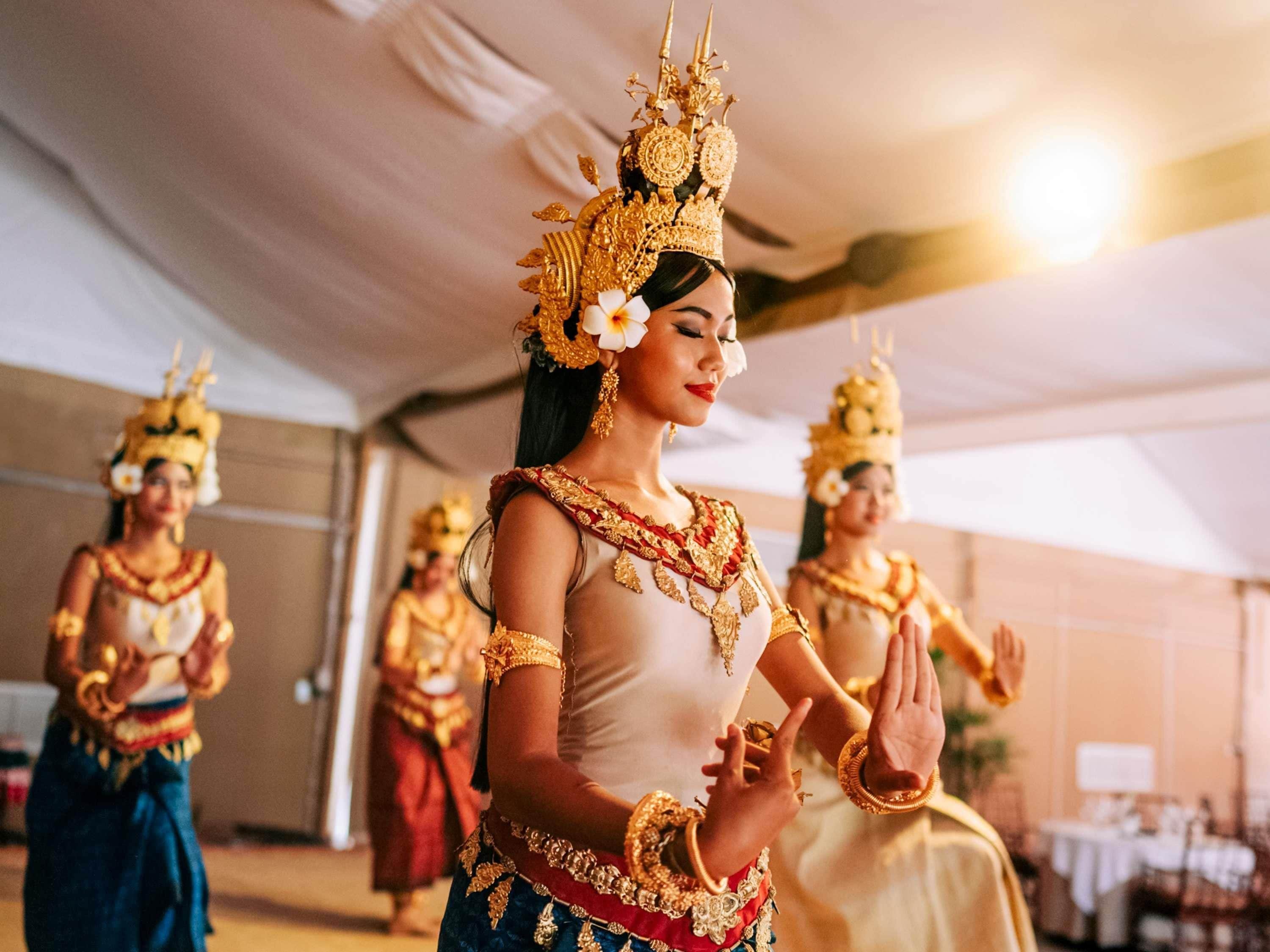 A group of people in traditional attire, likely performing a cultural dance, in a tent-like structure.