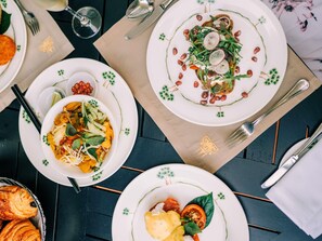 A table set with plates of food, cutlery, and a glass of wine.