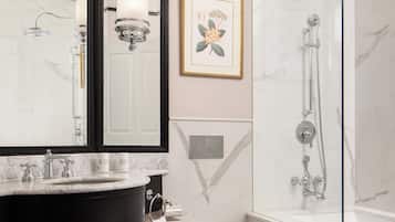 Un baño moderno con tocador negro, inodoro blanco y ducha con cerramiento de vidrio.