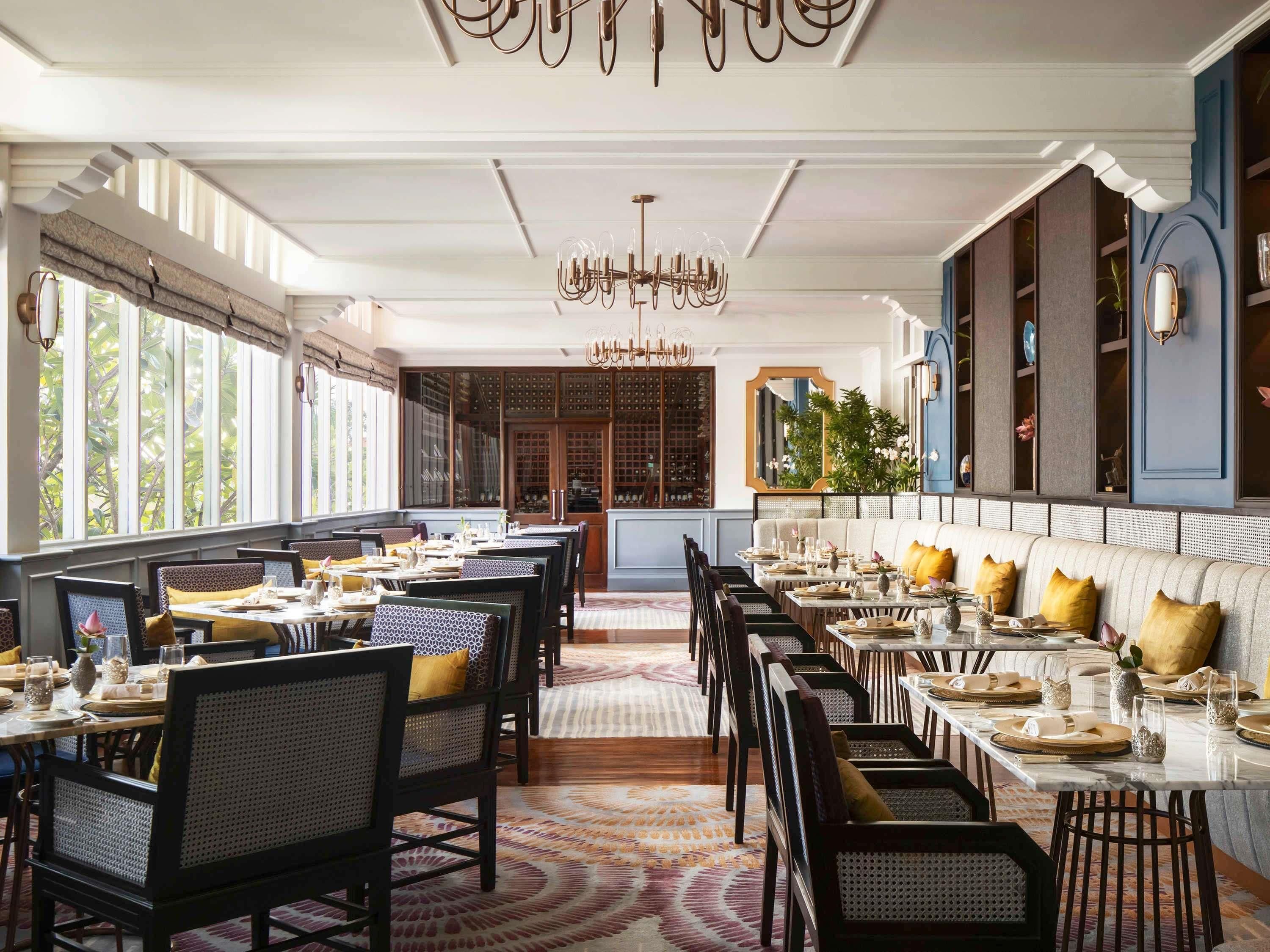 Un restaurante con varias mesas, sillas y una alfombra estampada.