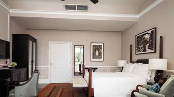 A hotel room with a bed, a desk, a chair, a television, and a ceiling fan.