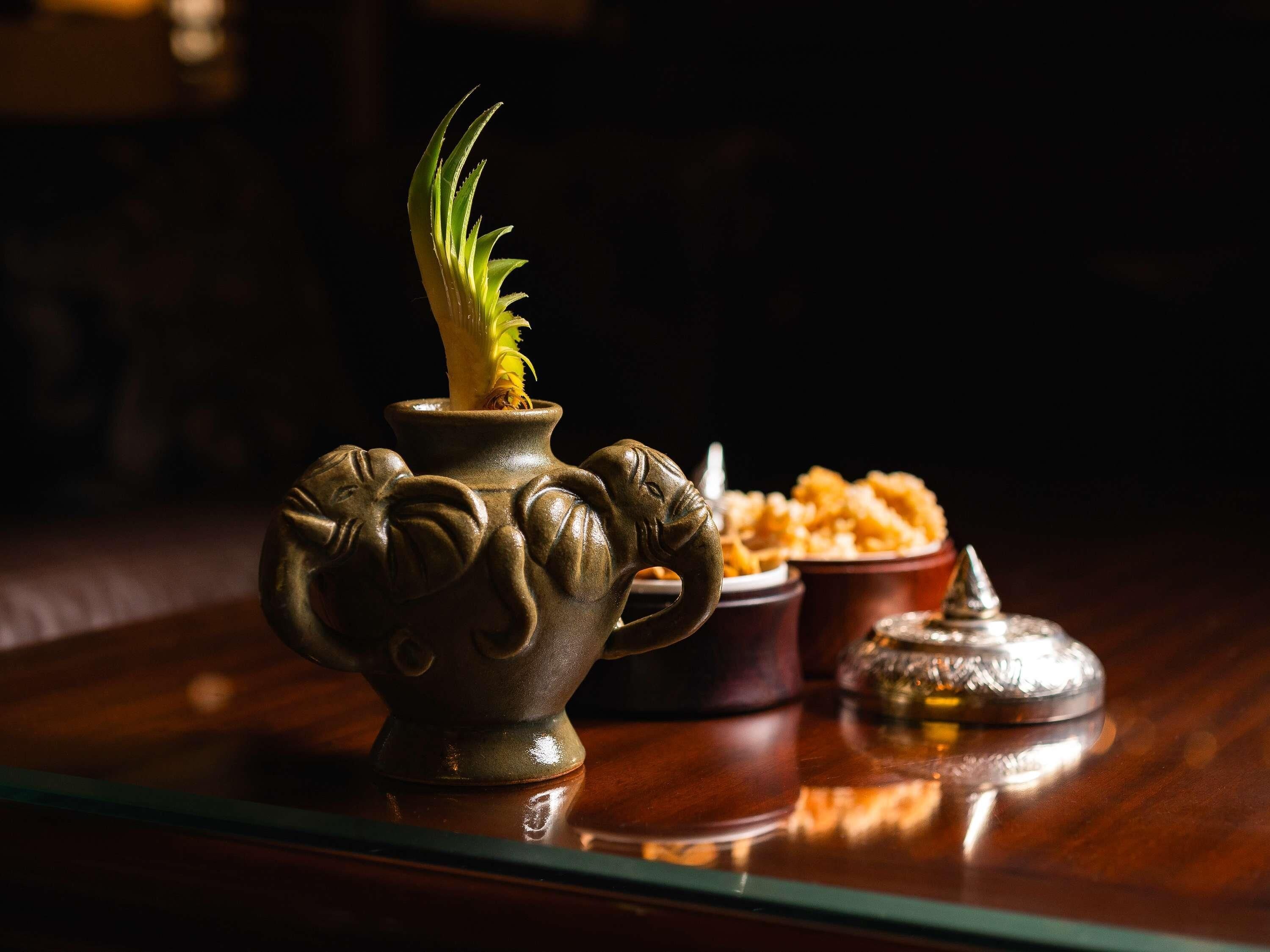 A decorative ceramic pot with a plant on a reflective surface.