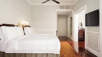 Ein Hotelzimmer mit einem großen Bett, einem Deckenventilator, einem Fernseher und einem Flur, der zu einem Badezimmer führt.