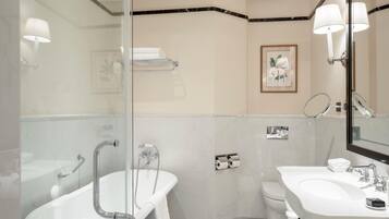 A modern bathroom with a glass-enclosed shower, a white bathtub, a sink, and a toilet.